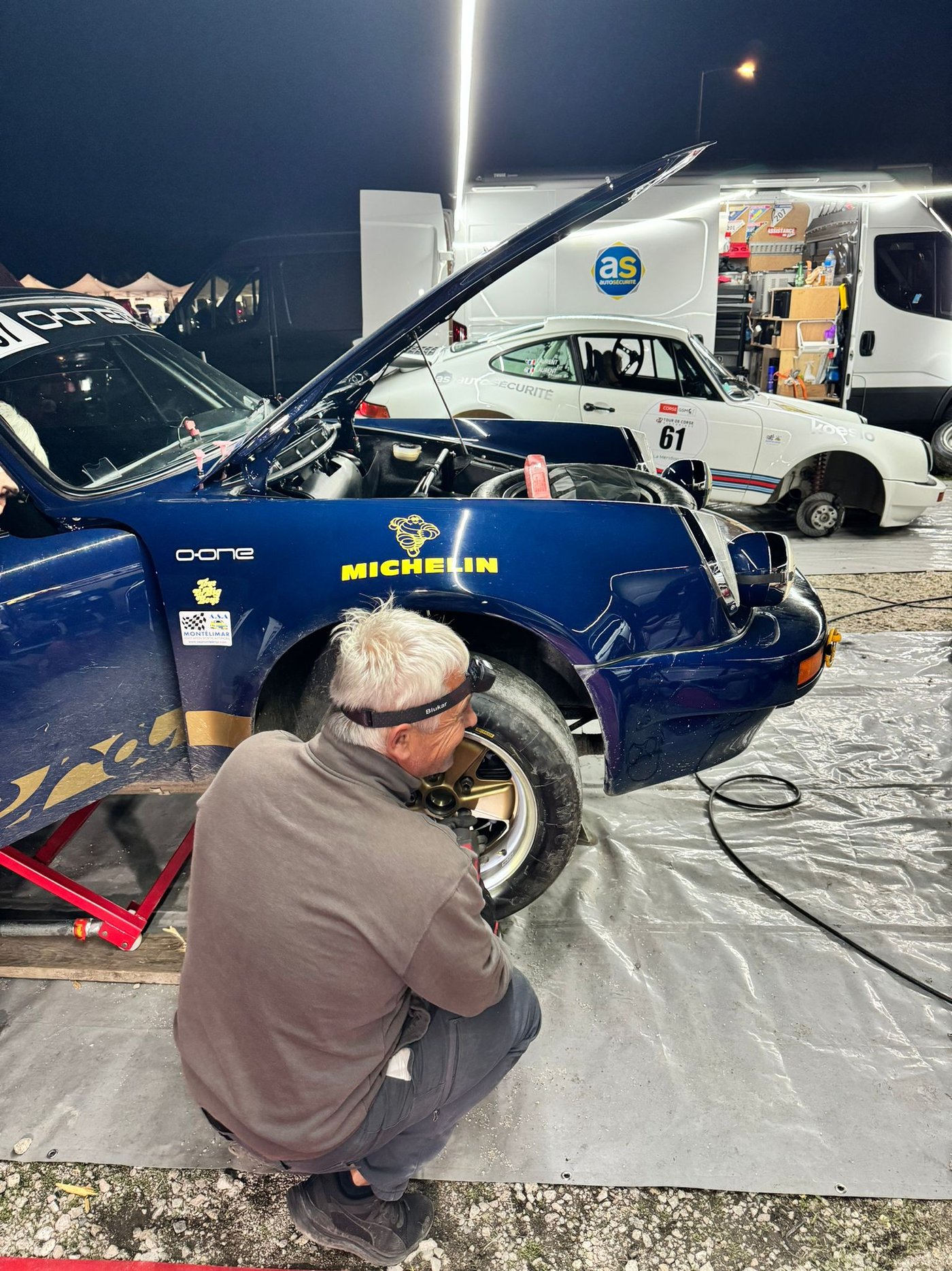 Mécanicien O-ONE remontant une roue de la Porsche 911 RSR, freins à nu, au Tour de Corse Historique