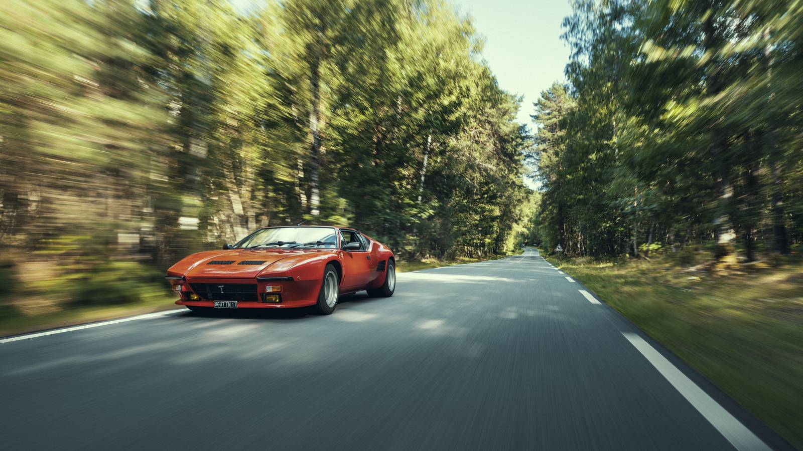 De Tomaso Pantera GT5-S rouge sur une route forestière après sa restauration