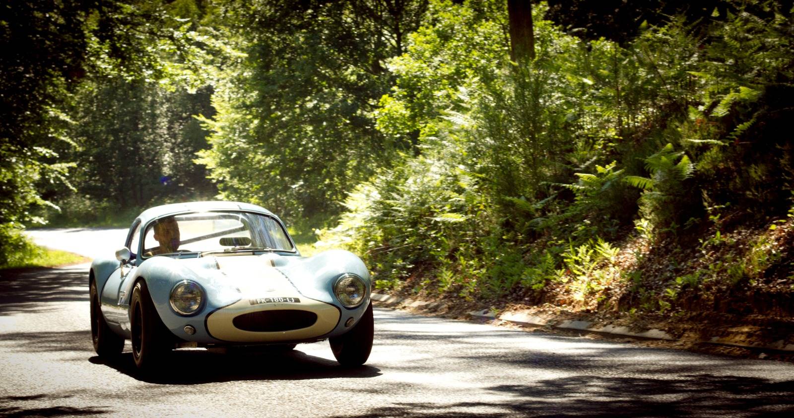 Ginetta G4 bleu clair sur une route de forêt, vue de trois quarts avant